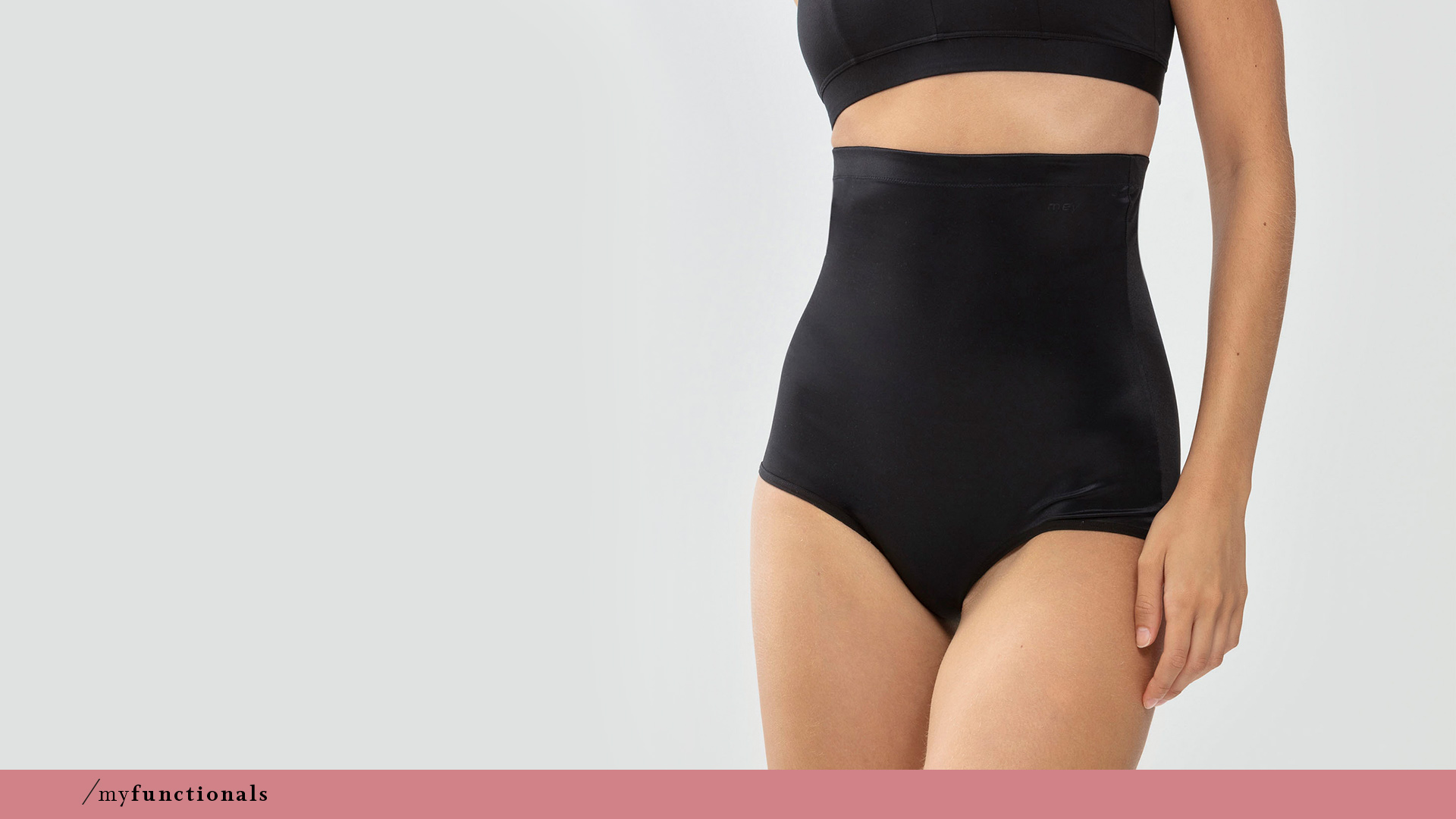 Woman wears black high-waisted briefs with shaping effect from the Cocoon series by mey®