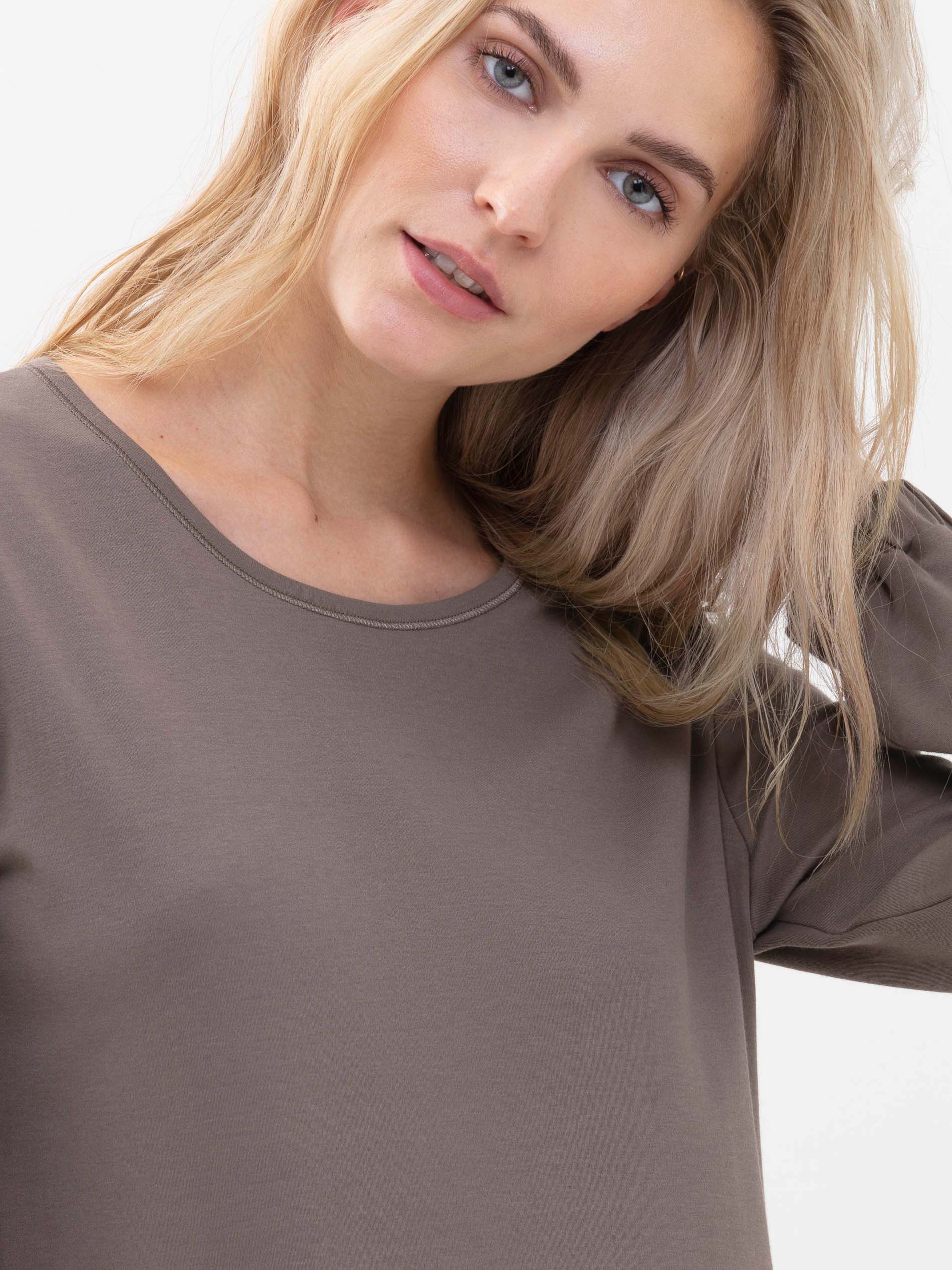 Front view of a blonde female model, wearing the long-sleeved shirt from the Zzzleepwear series in the colour Deep Taupe | mey®