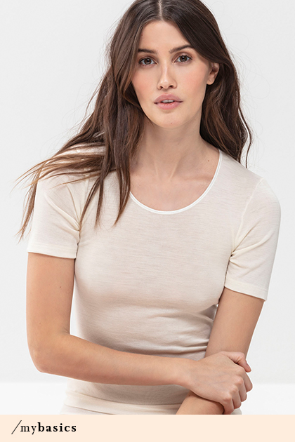Dame met lange, donkere haren draagt wit shirt van wol en zijde uit de serie Exquisite | mey®