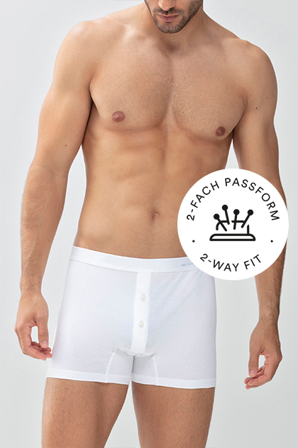 serie Casual Cotton, model draagt witte trunk-shorts, mey®-symbool voor tweevoudige pasvorm: speldenkussen met vier spelden | mey®