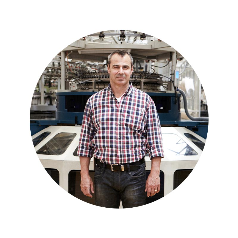 Employee portrait of Holger Teufel in front of a knitting machine in the knitting department | mey®