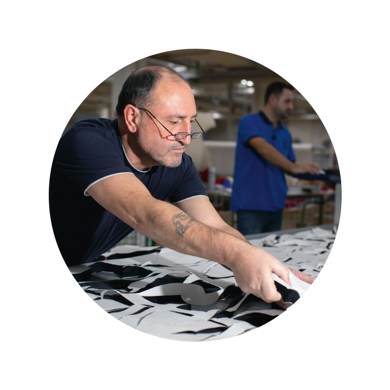 Mitarbeiter Portrait von Giuseppe Capobianco im Bereich Zuschnitt, er entnimmt gebündelte Zuschnittteile vom Schneidetisch | mey®