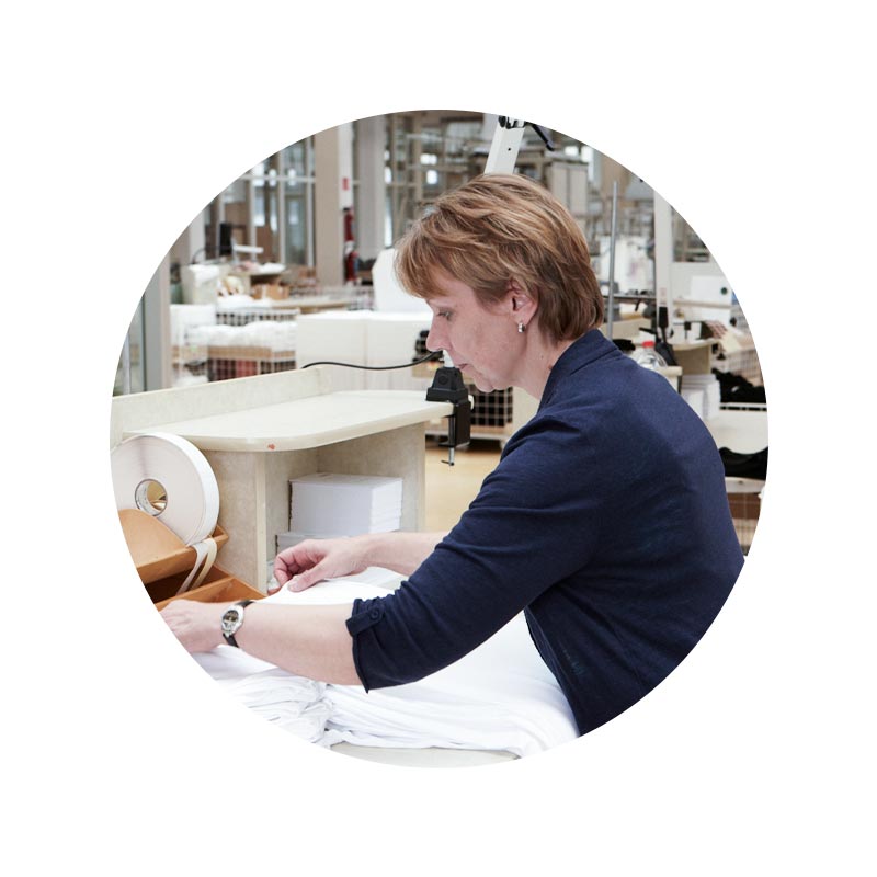 Mitarbeiter Portrait von Emica Zeller im Bereich Qualitätskontrolle beim Überprüfen von weißen Tops | mey®