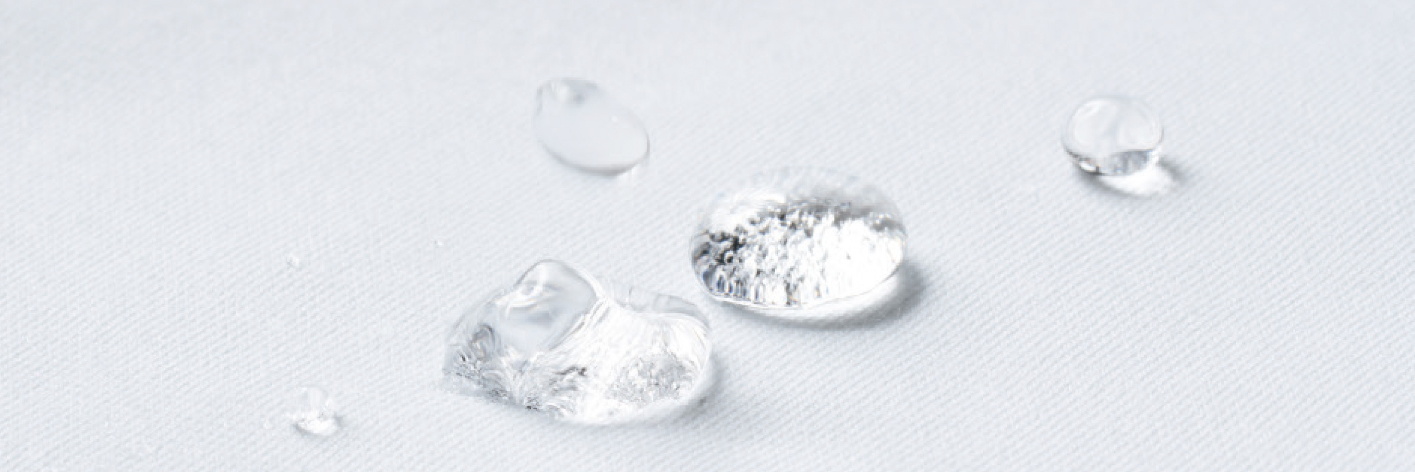 Waterdruppels liggen op een witte stof met hydrofobe eigenschappen | mey®