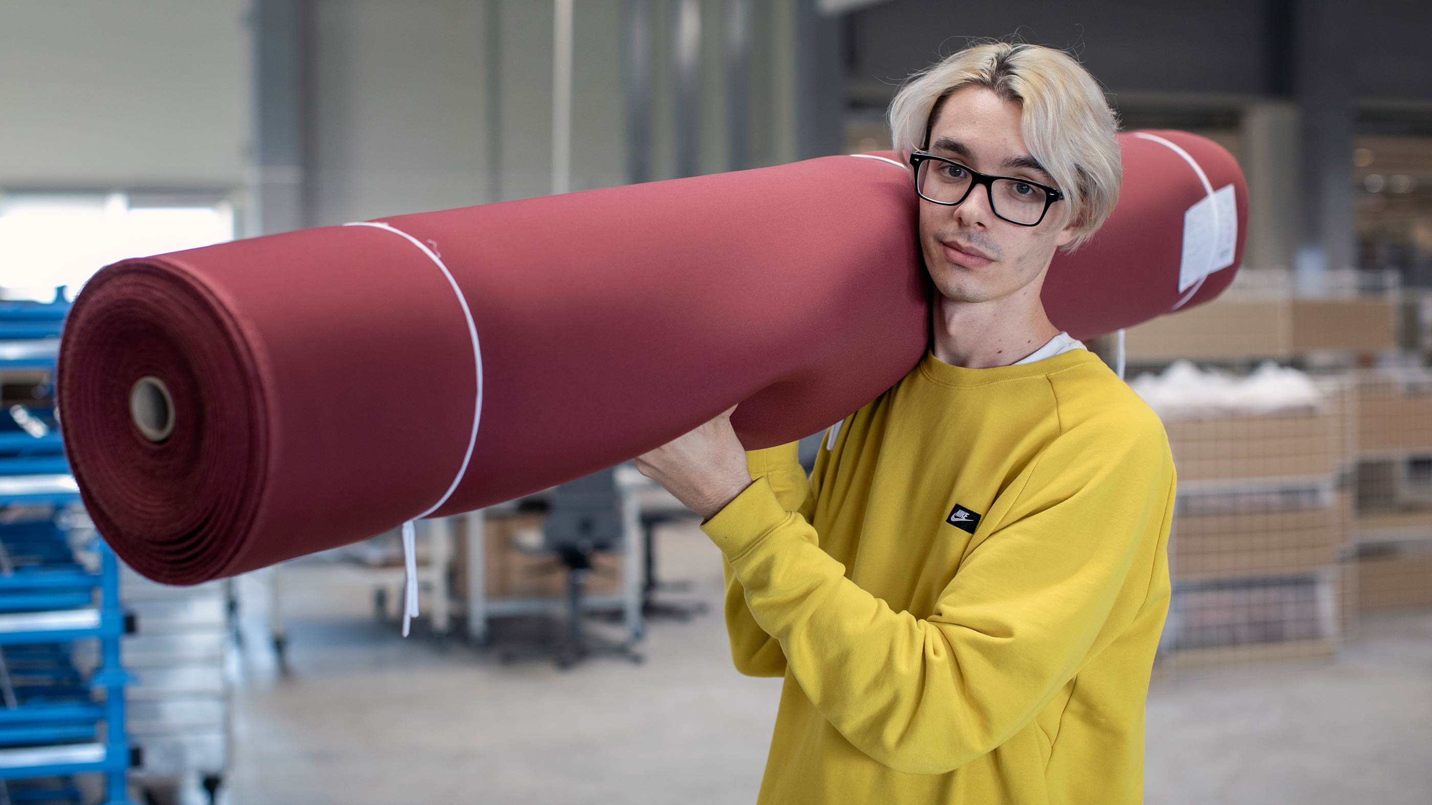 Employee carries a roll of burgundy fabric for further processing | mey®