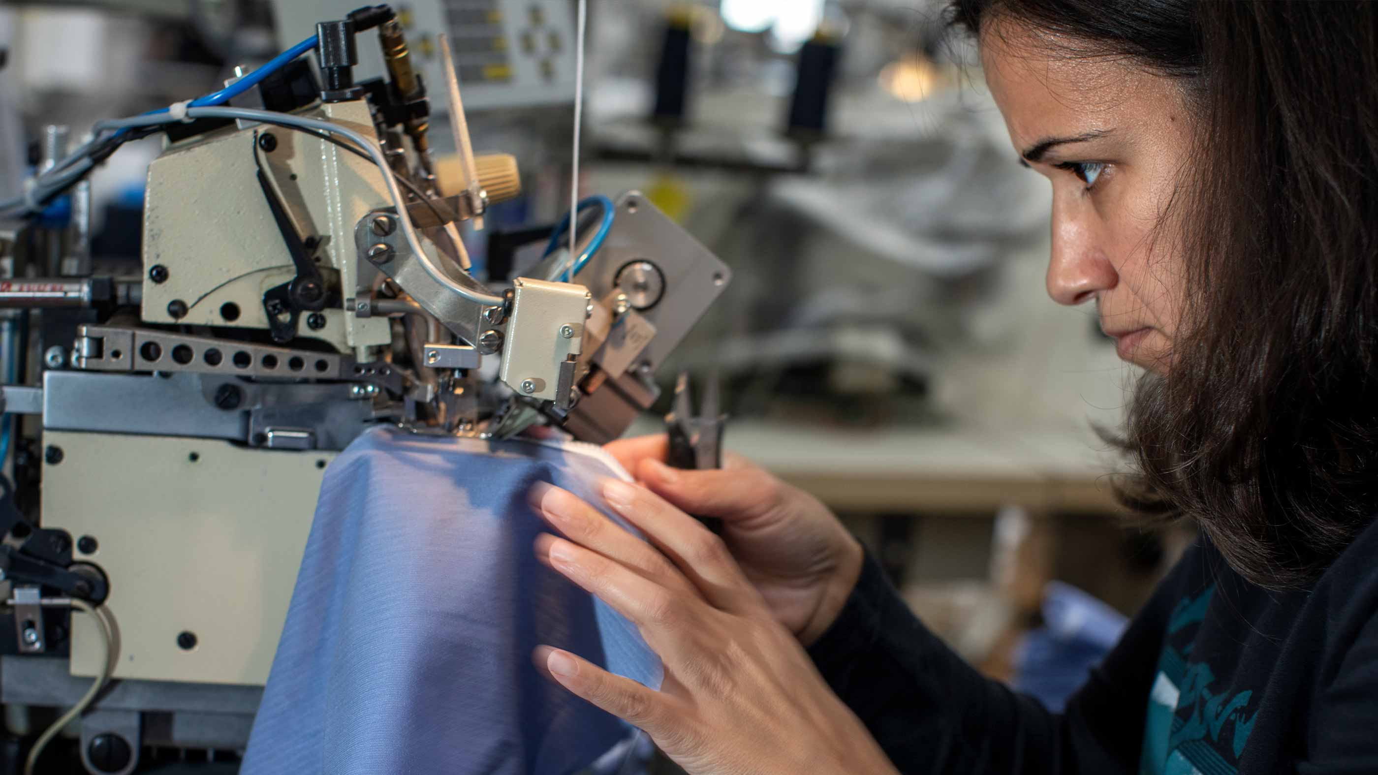Employee concentrates on sewing a blue item of underwear | mey®
