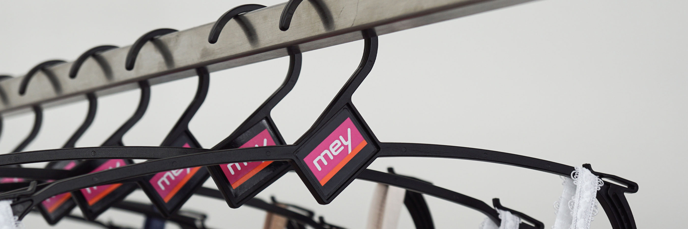 mey’s reusable hangers lined up on a clothing rail with clothing hanging from them | mey®