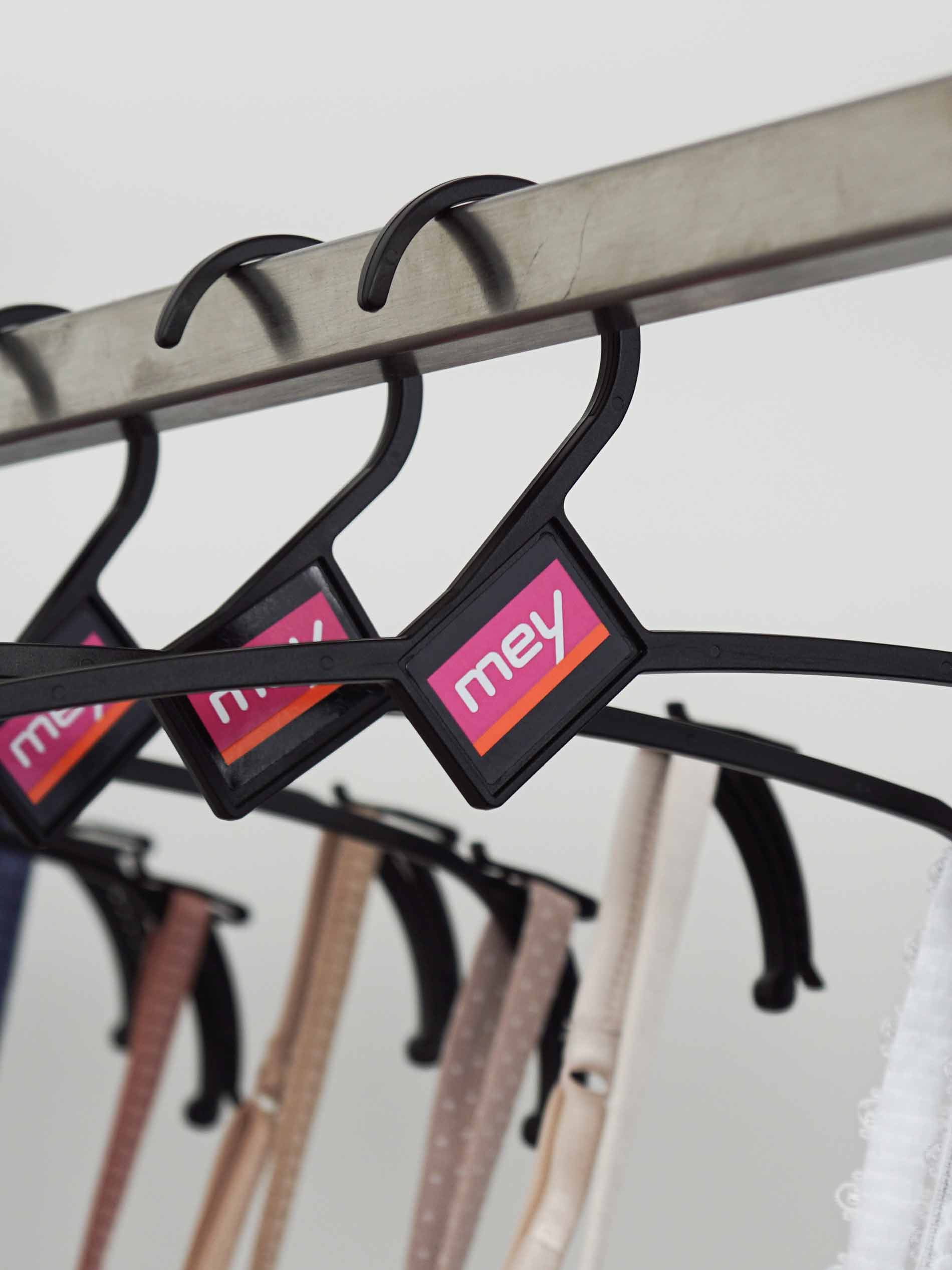 mey’s reusable hangers lined up on a clothing rail with clothing hanging from them | mey®