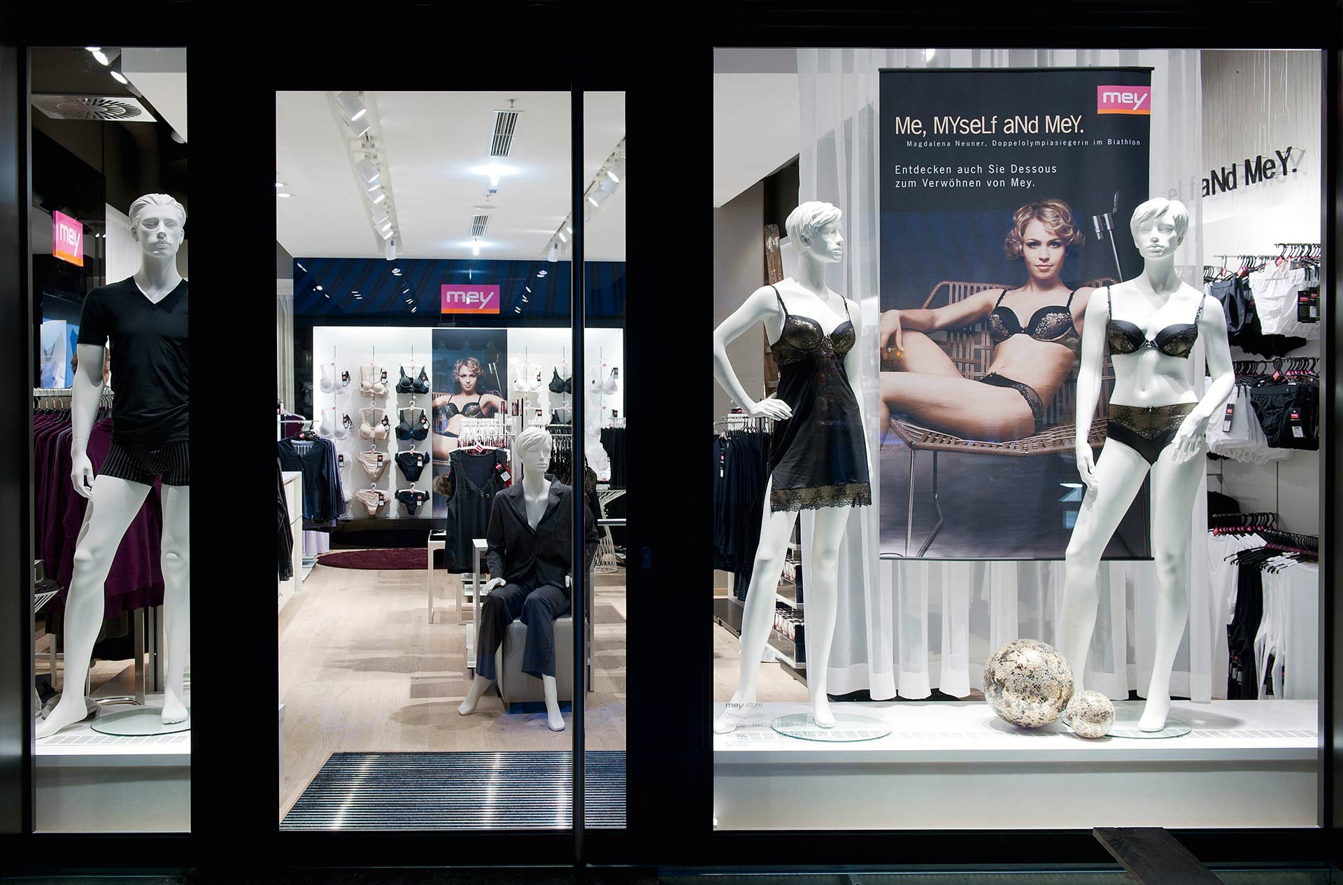 store in Wiesbaden, photographed from the outside with entrance doors, window mannequins and a mey advertising banner in the foreground | mey®